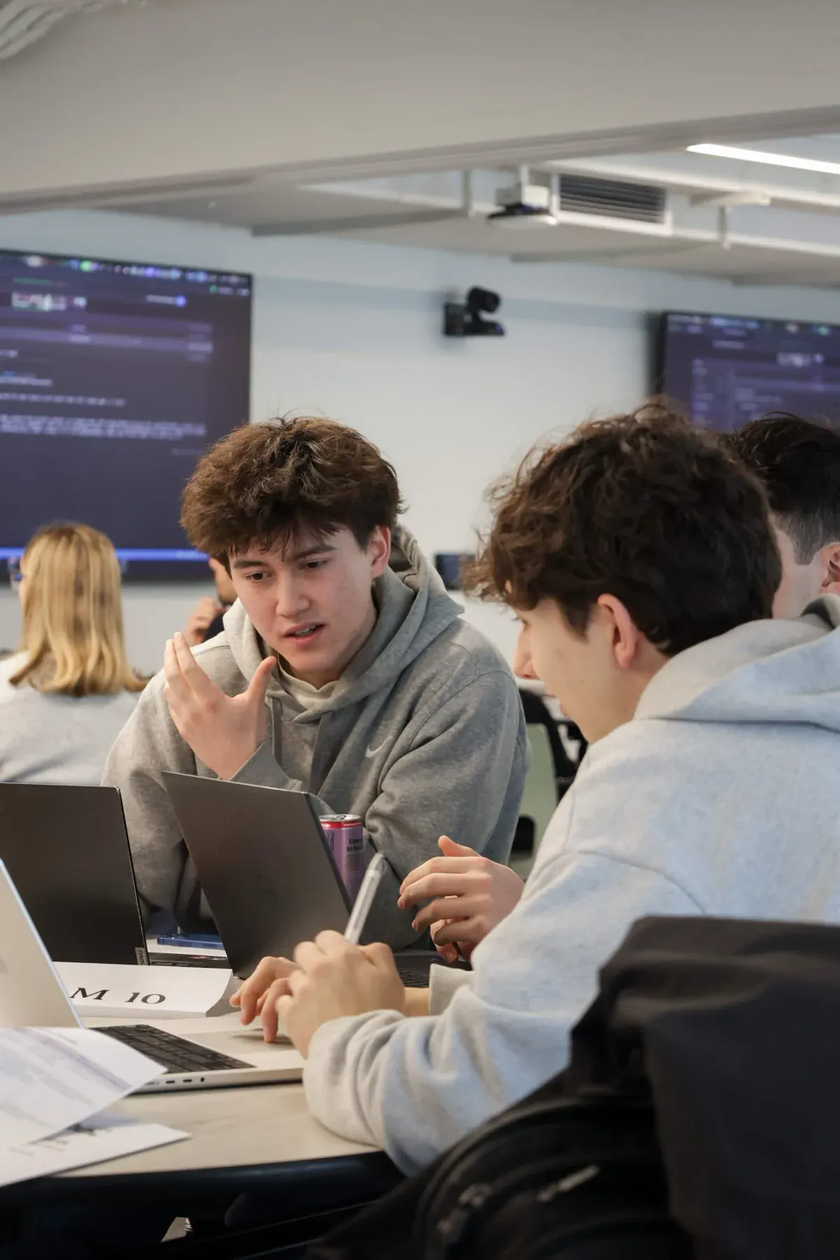 Students collaborating around laptops during an AINU build event